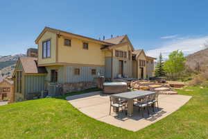 Back of house with a patio area, a yard, board and batten siding, and a mountain view