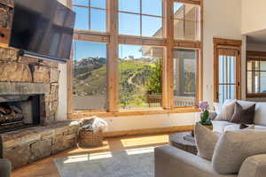 Living room with a high ceiling, wood finished floors, and a fireplace
