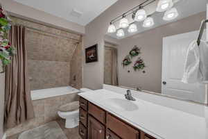 Full bathroom featuring shower / bathtub combination with curtain, vanity, tile patterned flooring, and toilet