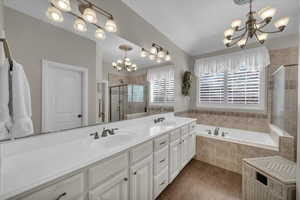 Bathroom featuring wood-type flooring, separate shower and tub, vanity, and a notable chandelier