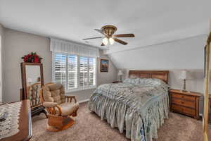 Carpeted bedroom featuring ceiling fan and vaulted ceiling