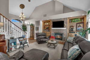 Carpeted living room with a brick fireplace, plenty of natural light, built in features, and high vaulted ceiling