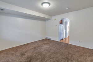 Carpeted empty room with a textured ceiling