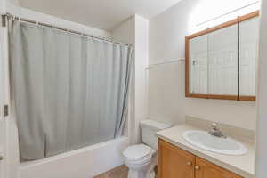 Full bathroom featuring shower / tub combo with curtain, vanity, and toilet