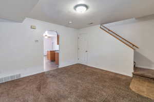 Unfurnished living room with carpet floors and a textured ceiling