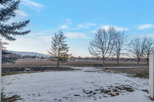 Yard covered in snow with a mountain view and a rural view