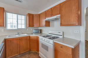 Kitchen featuring sink, dishwasher, and white gas stove