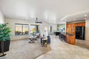 Living room with lofted ceiling, light tile patterned floors, sink, and ceiling fan