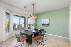 Dining space with light tile patterned floors and a chandelier