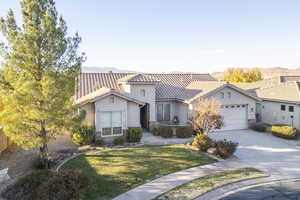 View of front of home with a garage, a mountain view, and a front lawn