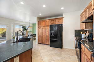 Kitchen featuring tasteful backsplash, light tile patterned flooring, sink, and black appliances