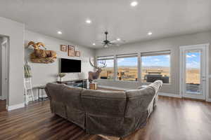 Living room featuring ceiling fan, dark wood-type flooring, and a textured ceiling