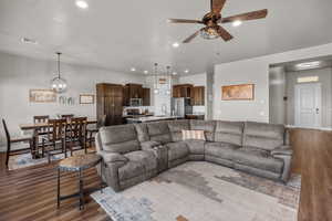 Living room with sink, dark hardwood / wood-style floors, and ceiling fan with notable chandelier