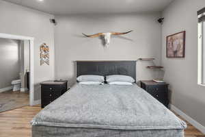 Bedroom with connected bathroom, hardwood / wood-style flooring, and ceiling fan