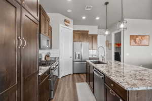 Kitchen with pendant lighting, sink, backsplash, a kitchen island with sink, and stainless steel appliances