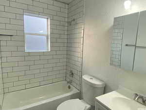 Full bathroom featuring tiled shower / bath, vanity, and toilet