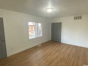 Unfurnished room featuring light hardwood / wood-style floors and a textured ceiling