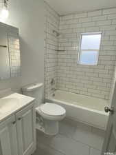 Full bathroom with tiled shower / bath, vanity, toilet, and tile patterned flooring