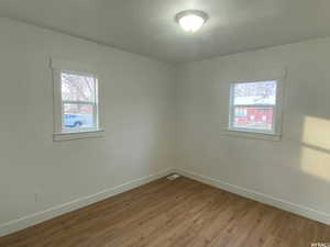 Empty room with light hardwood / wood-style flooring and a textured ceiling