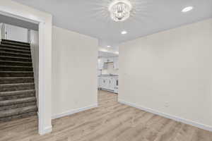 Unfurnished living room with an inviting chandelier and light wood-type flooring