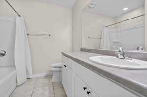 Full bathroom featuring shower / tub combo with curtain, vanity, tile patterned floors, and toilet