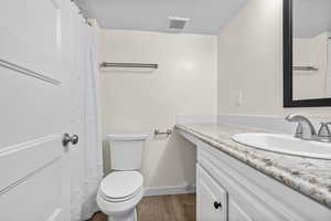 Bathroom featuring hardwood / wood-style flooring, vanity, a textured ceiling, and toilet