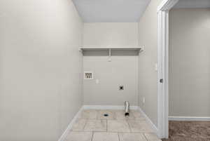 Laundry area with hookup for a washing machine, light tile patterned floors, a textured ceiling, and electric dryer hookup