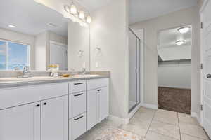 Bathroom featuring a shower with door, vanity, and tile patterned floors