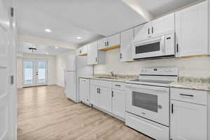 Kitchen with white appliances, sink, light hardwood / wood-style flooring, and white cabinets