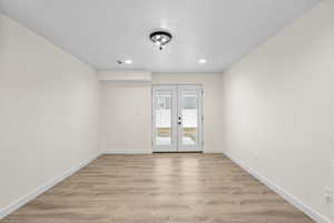 Unfurnished room with light hardwood / wood-style flooring and french doors