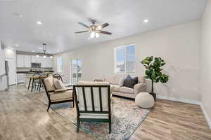 Living room with ceiling fan and light hardwood / wood-style floors