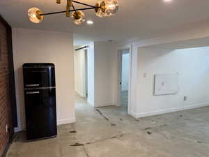 Interior space featuring concrete floors, brick wall, refrigerator, and a barn door