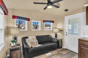 Living room featuring ceiling fan, lofted ceiling, and light hardwood / wood-style flooring