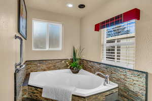 Bathroom featuring a healthy amount of sunlight and tiled bath