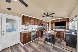 Kitchen with tasteful backsplash, vaulted ceiling, appliances with stainless steel finishes, a kitchen island, and ceiling fan