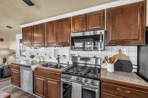 Kitchen with sink, backsplash, dark hardwood / wood-style flooring, stainless steel appliances, and a textured ceiling