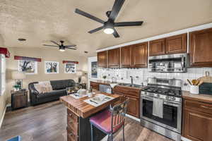 Kitchen featuring sink, dark wood-type flooring, stainless steel appliances, decorative backsplash, and vaulted ceiling