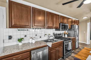 Kitchen featuring appliances with stainless steel finishes, tasteful backsplash, sink, dark hardwood / wood-style flooring, and ceiling fan