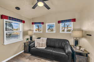 Living room with lofted ceiling, hardwood / wood-style flooring, and ceiling fan