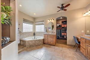 Bathroom with vanity, tile patterned floors, tiled bath, and ceiling fan