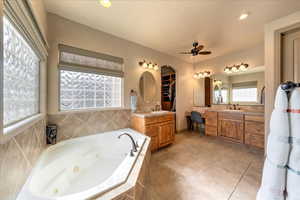 Bathroom with vanity, a relaxing tiled tub, tile patterned floors, and ceiling fan