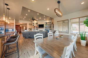 Dining room with ceiling fan with notable chandelier, built in features, and light hardwood / wood-style flooring