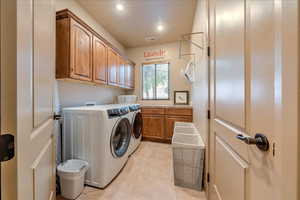 Laundry area featuring cabinets, separate washer and dryer, and light tile patterned floors