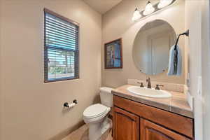 Bathroom with vanity, plenty of natural light, tile patterned floors, and toilet