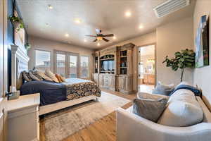 Bedroom featuring a textured ceiling, ensuite bath, ceiling fan, and light wood-type flooring