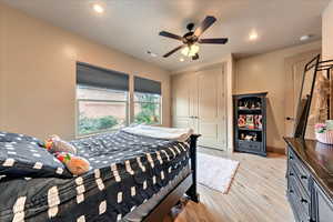 Bedroom with ceiling fan, light hardwood / wood-style floors, and a closet