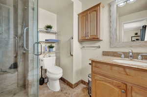 Bathroom with vanity, toilet, and a shower with shower door