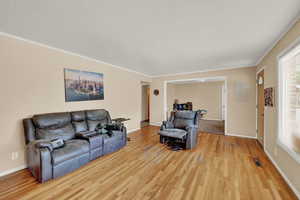 Living room featuring ornamental molding and light hardwood / wood-style floors