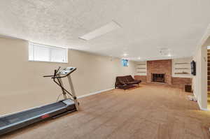 Workout area with carpet flooring, a brick fireplace, built in features, and a textured ceiling