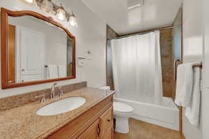 Full bathroom featuring shower / tub combo with curtain, vanity, toilet, and tile patterned flooring